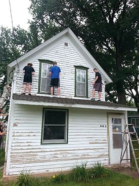 Students Alecia Koski, Chase Cole, and Derrick Marsh prepare a Correctionville, IA, home for painting. The group spent the day serving with Correctionville-based Atlas of the Valley; this house was part of the organization